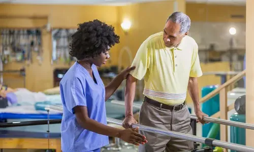 Physical therapist assistant helping patient regain balance while walking